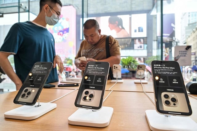 An Apple Store staff member (left) looks on as a shopper checks out an iPhone on display at the shop in Shanghai’s Huangpu district on Monday. Photo: AFP