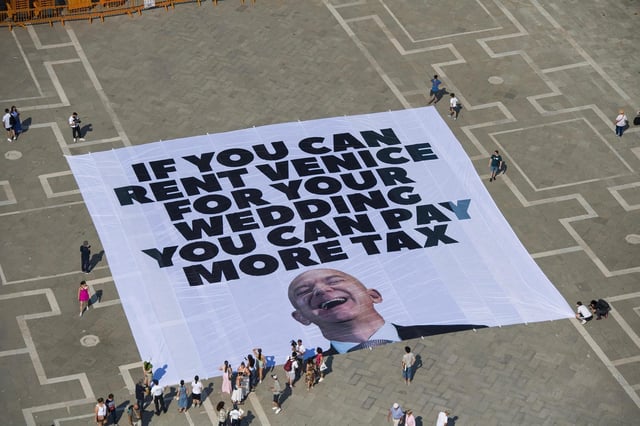 Des militants de Greenpeace ont déployé une bannière géante à l’effigie de Jeff Bezos place Saint-Marc, à Venise, le 23 juin, avec ce slogan : « Si vous pouvez louer Venise pour votre mariage, vous pouvez payer plus d’impôts. »
