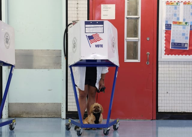 Une personne, accompagnée de son chien, vote dans un lycée de Manhattan pour la primaire qui doit désigner le candidat du Parti démocrate à la mairie de New York, le 24 juin 2025