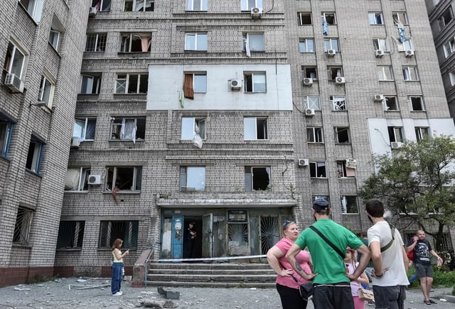 Residents stand near an apartment building that was damaged during a Russian missile strike in Dnipro on June 24, 2025.