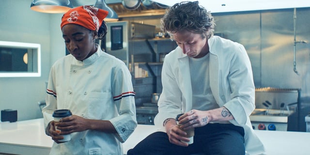 Jeremy Allen White as Carmy and Ayo Edebiri as Sydney side by side in the kitchen in Season 3 of The Bear