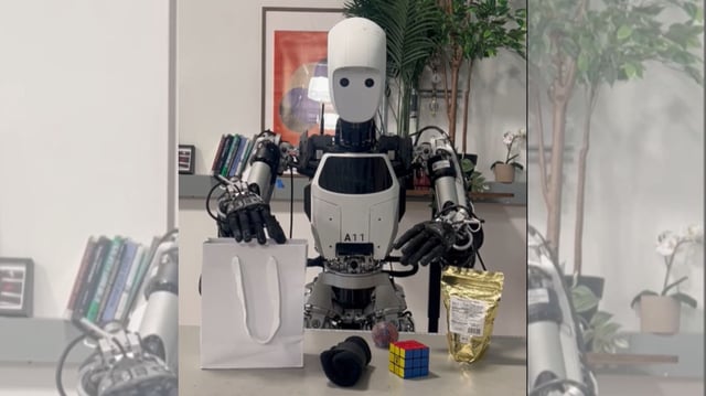In a robotics lab, Google’s humanoid robot A11 demonstrates task-ready posture in front of assorted items, representing the kinds of real-world scenarios its offline AI model is built to handle autonomously