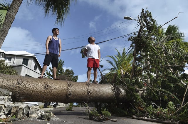 The first named storm of the Atlantic hurricane season has formed east of Bermuda. Men stand on a tree felled by Hurricane Humberto, on Pitts Bay Road in Hamilton, Bermuda, Thursday, Sept. 19, 2019. THE CANADIAN PRESS/AP-Akil J. Simmons