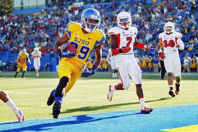 Wide receiver Chandler Jones #89 of the San Jose Spartans scores on a 19-yard touchdown pass against defensive back Curtis Riley #7 and safety Derron Smith #13 of the Fresno State Bulldogs in the first quarter on November 29, 2013 at Spartan Stadium in San Jose, California.