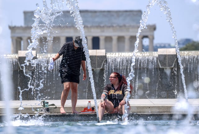 People cool their feet in a water feature at the World War II Memorial, amid a dangerous heat wave afflicting the eastern half of the United States, in Washington, U.S., June 24, 2025. REUTERS/Evelyn Hockstein