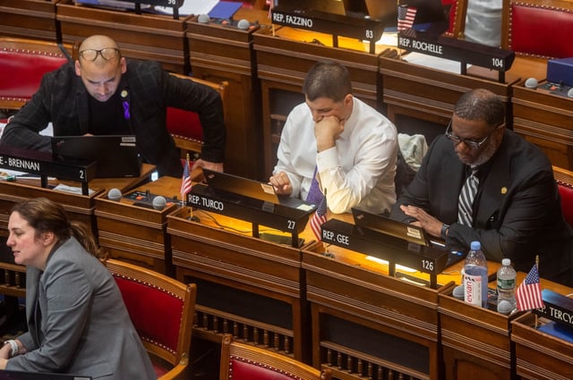 State Rep. Raghib Allie-Brennan (D-Bethal) left, State Rep. Gary Turco (D-New Britain) and State Rep. Fred Gee (D-Bridgeport) works at their seats as LCO 8797 Senate Amendment A: Substitute for S.B. 7: An Act Strengthening Protections for Connecticut&#39;s Consumers of Energy is discussed in the House Chambers on Monday, June 6, 2023. (Aaron Flaum/Hartford Courant)
