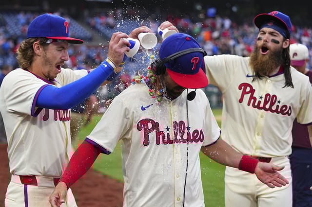 Bryson Stott #5 and Brandon Marsh #16 of the Philadelphia Phillies pour water and candy on Whit Merrifield #9 after the game against the San Francisco Giants at Citizens Bank Park on May 6, 2024 in Philadelphia, Pennsylvania.
