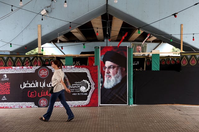 A woman walks past a poster with an image of the late Hezbollah leader Hassan Nasrallah, killed in an Israeli airstrike last fall, in the southern suburbs of Beirut June 23, 2025. 