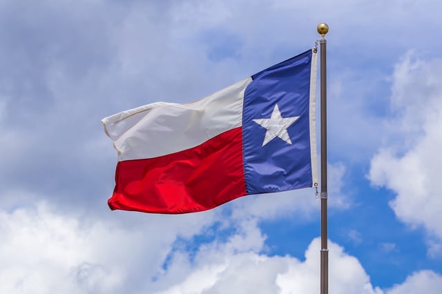 FILE: State of Texas flag against cloudy sky outdoors.
