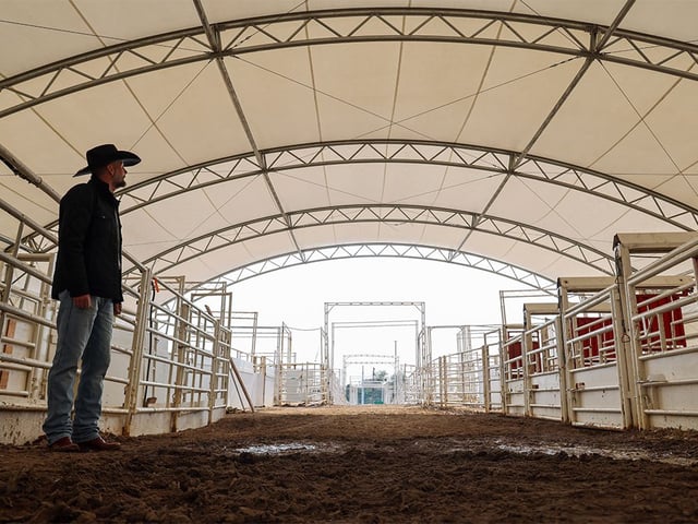  Calgary Stampede Agriculture & Western Events manager Brett Warder stands beneath a covered area behind the rodeo infield that provides shade for horses and livestock on Tuesday, June 24, 2025. The Calgary Stampede is studying ways to keep animals cool and adding more shade is one of the areas of research.