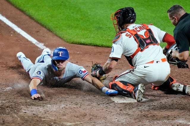 Texas Rangers&#39; Evan Carter, left, scores past Baltimore Orioles catcher Gary Sanchez (99) on an RBI hit by Sam Haggerty during the tenth inning of a baseball game, Tuesday, June 24, 2025, in Baltimore. (AP Photo/Stephanie Scarbrough)