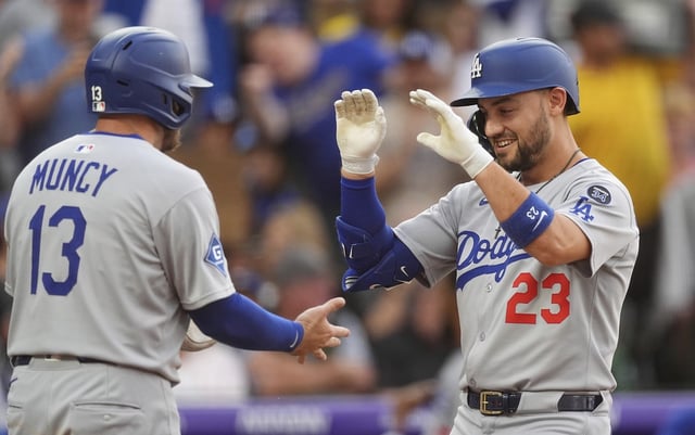 The Dodgers’ Max Muncy, left, congratulates Michael Conforto as he crosses home plate after hitting a three-run home run during the fourth inning of their game against the Colorado Rockies on Tuesday night in Denver. The Dodgers held on for a 9-7 won. (AP Photo/David Zalubowski)