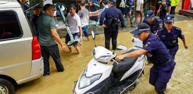 Une équipe aide à déplacer du matériel dans une rue inondée à Congjiang, dans la province de Guizhou, au sud-ouest de la Chine, le 24 juin 2025