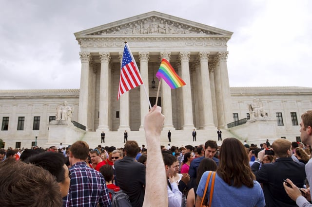 In this June 26, 2015 file photo, a man holds a US and a rainbow flag outside the Supreme Court in Washington after the court legalized gay marriage nationwide.