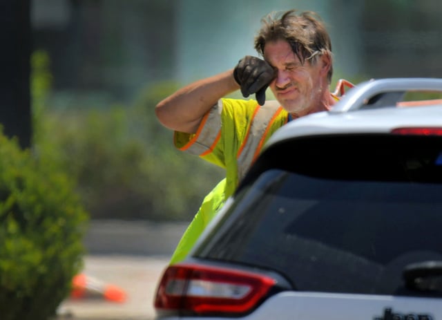 As local temperatures flirt with 100º Richard Lord takes a break, wiping his brow while digging with other personnel of E2CR, Inc. as a passing vehicle waits for a traffic signal at Pratt Street near Howard Street. The geotechnical drilling company plans to test the foundational viability beneath the street for the proposed Red Line light rail project. (Karl Merton Ferron/Staff)