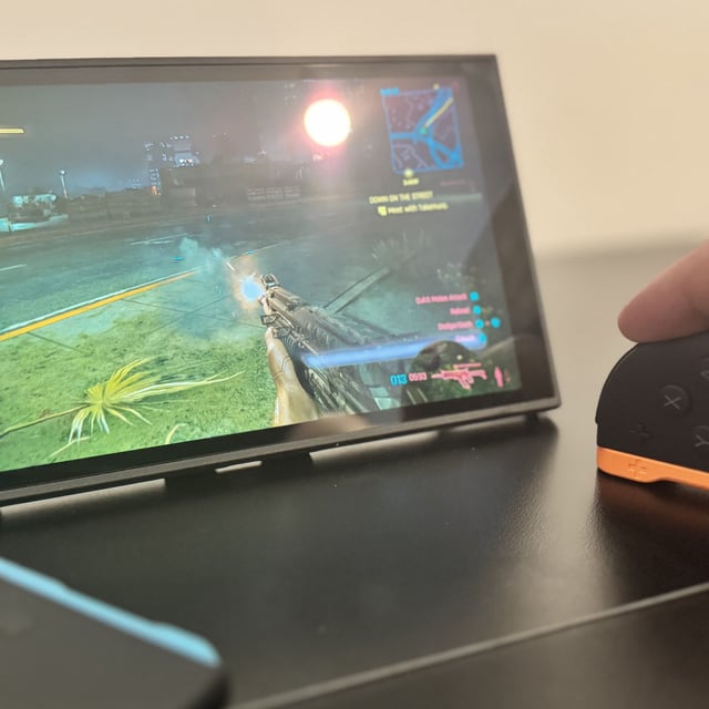 A picture of a Nintendo Switch 2, in mouse mode, with Cyberpunk 2077 in the background