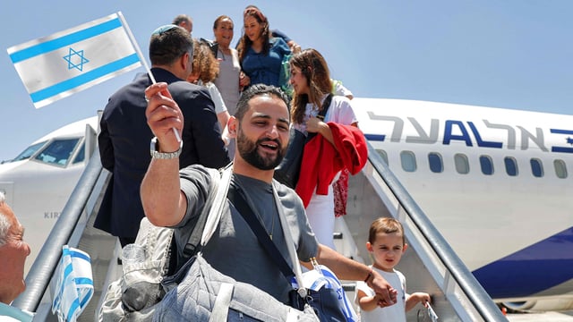 Jewish migrants making Aliyah (immigration to Israel) are handed miniature Israeli flags upon disembarking from an Israeli El Al airlines aircraft after their arrival at Ben Gurion Airport in Lod on June 25, 2025.