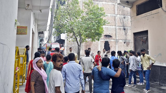 Locals gathered as Firefighters try to douse a fire that broke out in a factory, at Rithala, in New Delhi, India, on Wednesday, June 25, 2025. 