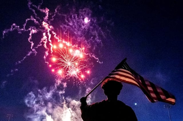 Nathan Milliman, 16, of Montclair, waves an American flag as fireworks from a Fourth of July celebration fill the sky above Ayala Park in Chino on Saturday, July 2, 2022. (Photo by Watchara Phomicinda, The Press-Enterprise/SCNG)