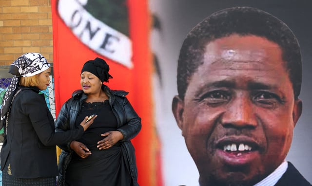 Mourners gather in front of a banner ahead of the funeral of Zambia's former President Edgar Lungu, who died on June 5 while receiving treatment for an undisclosed illness in a South African hospital, before a church service at the Cathedral of Christ the King, and a private burial, in Hillbrow, Johannesburg June 25, 2025. REUTERS/Siphiwe Sibeko