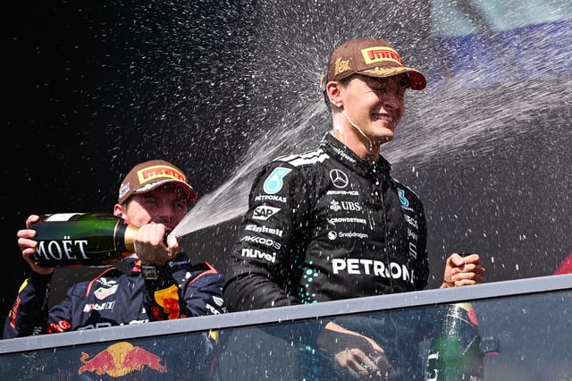 Jun 15, 2025; Montreal, Quebec, Canada; Second place Red Bull Racing driver Max Verstappen (1) sprays champagne on winner Mercedes driver George Russell (63) at Circuit Gilles-Villeneuve. Mandatory Credit: David Kirouac-Imagn Images