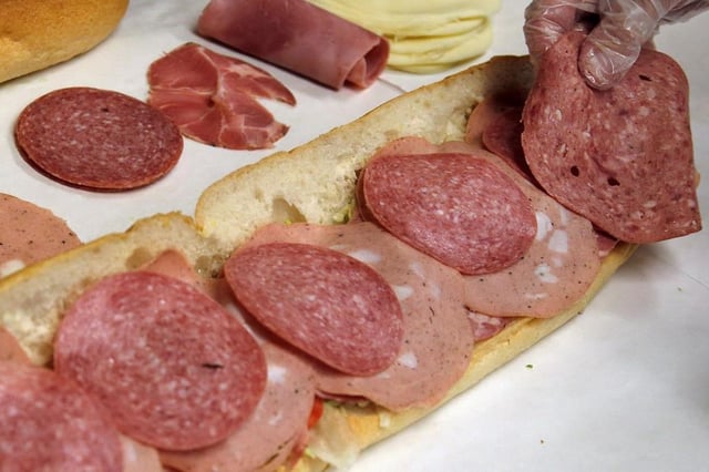 FILE - In this June 5, 2014, file photo, a man makes a submarine sandwich with mortadella, cooked salami, ham, Genoa salami and sweet capicola at a delicatessen.