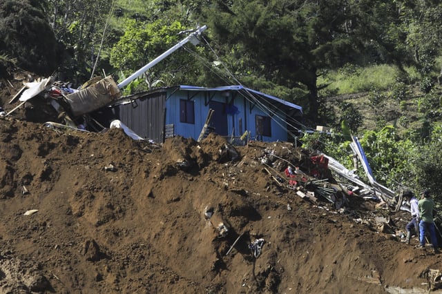 People look at their destroyed home after a deadly landslide was triggered by heavy rain in Bello, Antioquia state, Colombia, Wednesday, June 25, 2025. (AP Photo/Fredy Amariles)