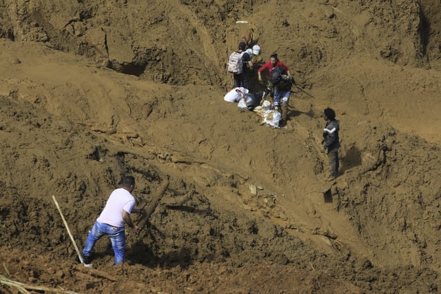Residents evacuate with what they can carry after a deadly landslide was triggered by heavy rain in Bello, Antioquia state, Colombia, Wednesday, June 25, 2025. (AP Photo/Fredy Amariles)