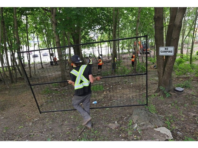 A contractor carries fencing after city compliance staff officially closed off the site of the former Geary Street homeless encampment in Dartmouth Wednesday June 25, 2025. The three remaining people here were asked  to pack their belongings for transportation or storage and to vacate the site.
