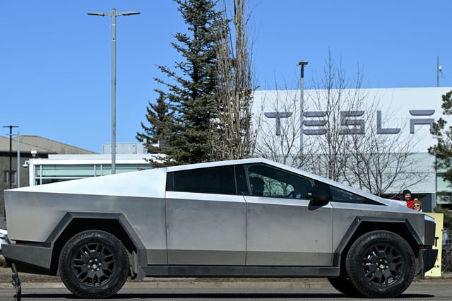 A Tesla Cybertruck drives past people gathered outside a Tesla dealership during a rally protesting CEO Elon Musk’s political involvement in Edmonton, Canada, on March 22, 2025.