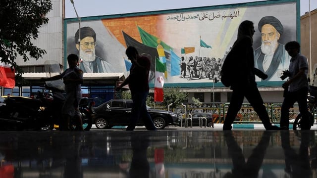People walk next to a mural with a picture of Iran's Supreme Leader, Ayatollah Ali Khamenei, on a street, early hours of ceasefire, in Tehran, Iran, on June 24. 