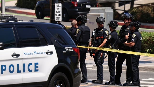 Police in tactical gear gather during a search for a suspect, after a police officer was shot near the Santa Monica Place mall. 