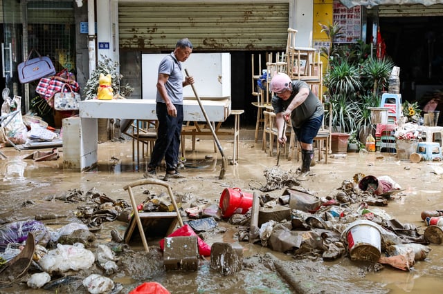 Residents clean up debris on a street after floodwaters receded in Rongjiang county, Guizhou province, China, June 25. via cnsphoto