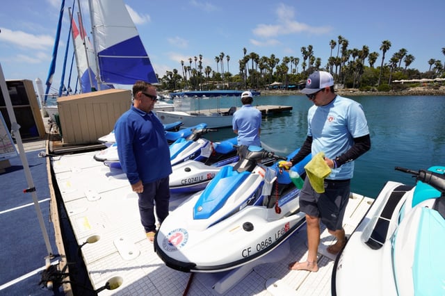 At one of his five Action Sport Rentals locations, owner Steve Pinard (l) checks in on his staff, Noah Pavlik (m) and Richie Snow (r), at the docks of Paradise Point Resort &amp; Spa on Wednesday, June 25, 2025, in San Diego, CA. Pinard estimates that by peak season, he will employ as many as 100 workers across his five locations. The proposal for a $25 minimum wage for tourism workers moves to the full City Council for consideration.