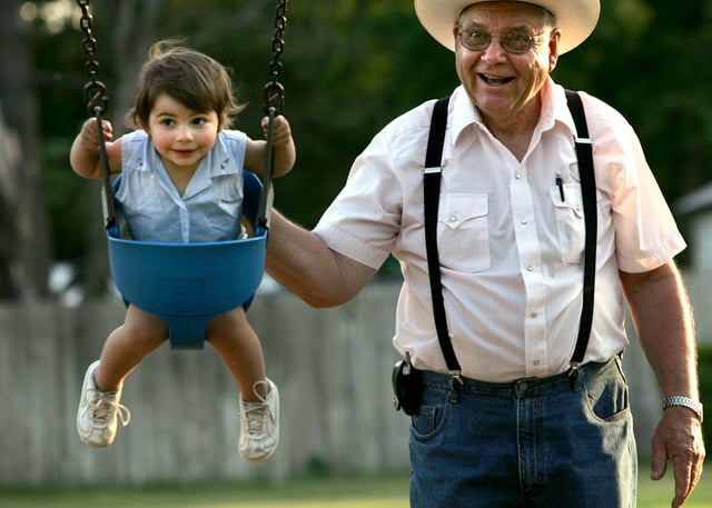 File photo: a grandfather pushes his granddaughter on a swing.