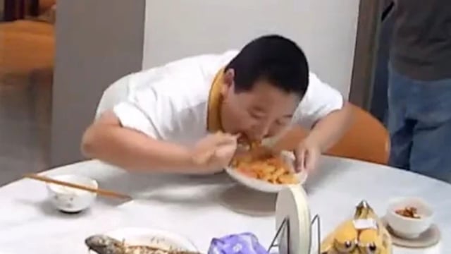screenshot of young boy eating food on table