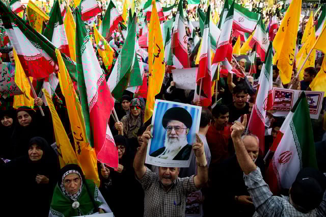 People are pictured holding flags of Iran and Hezbollah, as well as posters of Supreme Leader Ayatollah Ali Khamenei, in downtown Enghelab (Revolution) Square in Tehran.