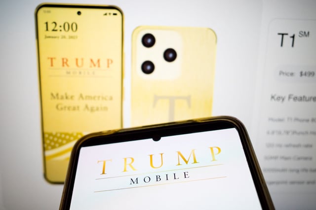  The Trump Mobile logo appears on a smartphone screen, and the website of Trump Mobile is on a laptop screen in the background, in this photo illustration.