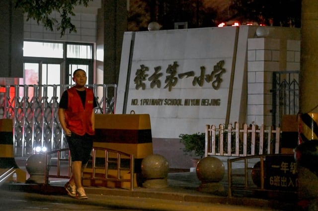 A man walks past the No.1 Primary School near where a crash incident occurred in Miyun, north of Beijing