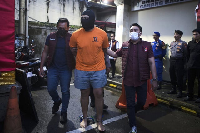 Indonesian police officers escort Australian M.C., one of the suspects in the fatal shooting of an Australian tourist, ahead of a press conference at the local police precinct in Badung, Bali, Indonesia on Thursday, June 26, 2025. (AP Photo/Firdia Lisnawati)