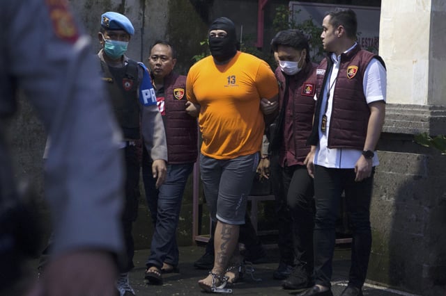 Indonesian police officers escort Australian T.P., one of the suspects in the fatal shooting of an Australian tourist, ahead of a press conference at the local police precinct in Badung, Bali, Indonesia on Thursday, June 26, 2025. (AP Photo/Firdia Lisnawati)