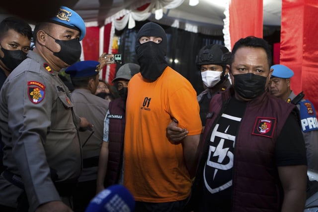 Indonesian police officers escort Australian D.J.F., one of the suspects in the fatal shooting of an Australian tourist, ahead of a press conference at the local police precinct in Badung, Bali, Indonesia on Thursday, June 26, 2025. (AP Photo/Firdia Lisnawati)