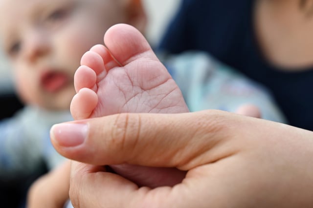 A mother holds her baby's foot in Saxony, Leipzig, on May 7, 2025.