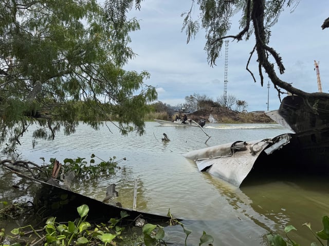 Debris from a SpaceX spacecraft lies partially submerged in the Rio Grande River as a boat navigates nearby, as seen from Matamoros, Mexico, June 19, 2025. REUTERS/Abraham Pineda/File Photo