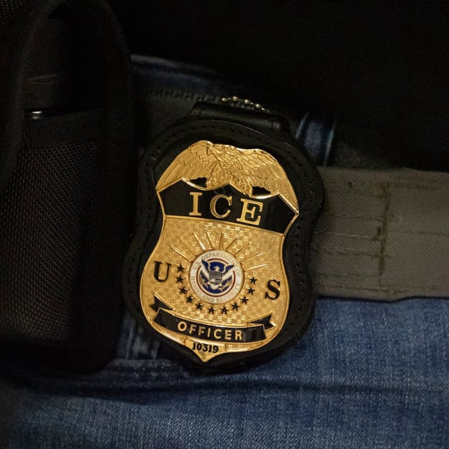 A federal agent wears a badge of Immigration and Customs Enforcement while standing outside an immigration courtroom at the Jacob K. Javits Federal Building in New York on Tuesday, June 10, 2025. (AP Photo/Yuki Iwamura)