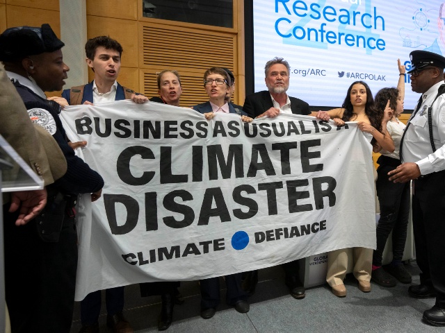 Climate protestors stand on stage after interrupting a speech by Federal Reserve Chairman Jerome Powell at the 24th Jacques Polak Research Conference at the International Monetary Fund on Thursday, Nov. 9, 2023 in Washington. (Mark Schiefelbein/AP)