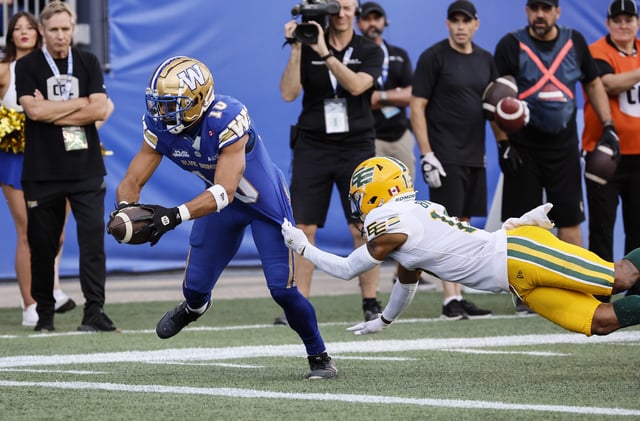 Winnipeg Blue Bombers' Nic Demski (10) reaches out for the touchdown against Edmonton Elks' Devodric Bynum (16) during first half CFL action in Winnipeg Thursday, June 26, 2025.    THE CANADIAN PRESS/John Woods