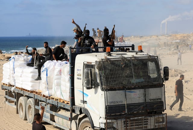 Palestinians from clans hold guns and melee weapons to secure aid trucks in Beit Lahia, in the northern Gaza Strip, June 25, 2025. REUTERS/Dawoud Abu Alkas/File Photo