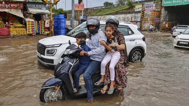 Commuters move through a waterlogged road after heavy rainfall, at Jhotwara area, in Jaipur, Rajasthan.