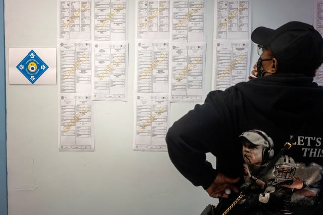 A woman looks at sample ballots while waiting at City Hall to cast her ballot for the upcoming presidential election as early voting begins in New Orleans, Louisiana, U.S., October 16, 2020. REUTERS/Kathleen Flynn/File Photo